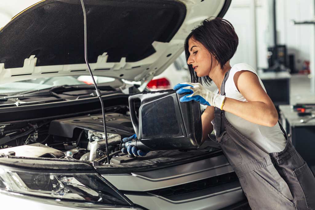 lady pouring transmission fluid into car